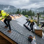 Expert roof installers from Paragon Roofing BC installing shingles on a Vancouver residential roof with misty background.