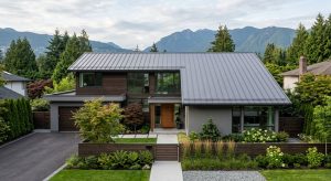 A contemporary Vancouver home featuring a newly installed standing seam metal roof with charcoal gray panels, neat landscaping, and North Shore mountains in the background.